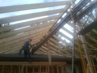 Rafters going up over a new addition with a worker on the wall in Rio Rancho
