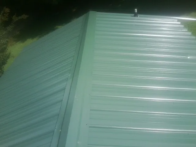 New green metal panels meeting at the ridge of a roof — Flat Roof Repair work by our crew in Rio Rancho