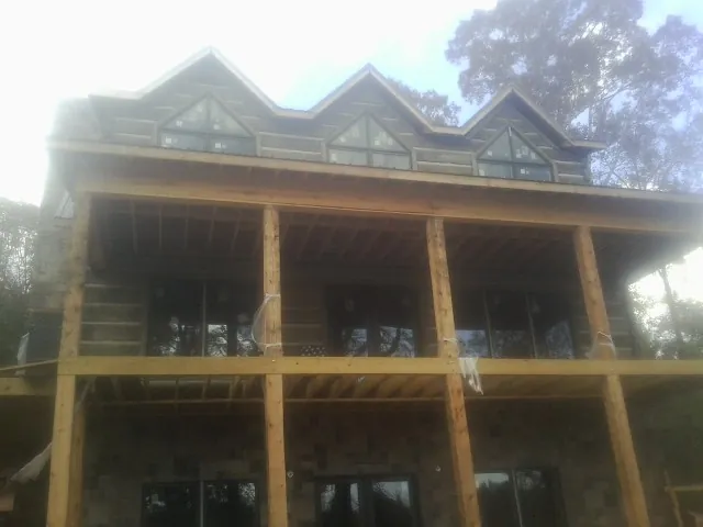 Dormers and porch framing on a large log home under construction — Roof Coating work by our crew in Rio Rancho