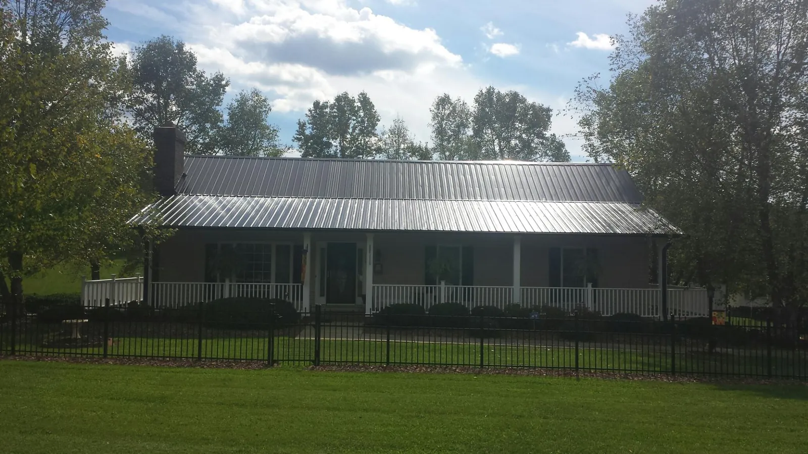 Gray metal roof on a brick ranch with a full width front porch — Gutter Guard Installation work by our crew in Rio Rancho