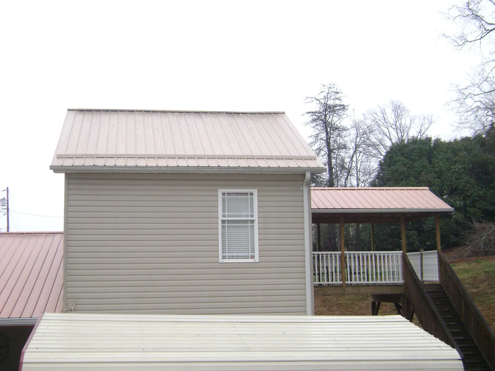 Tan metal roofs on a two story addition and attached porch, from a Roof Replacement job in Rio Rancho