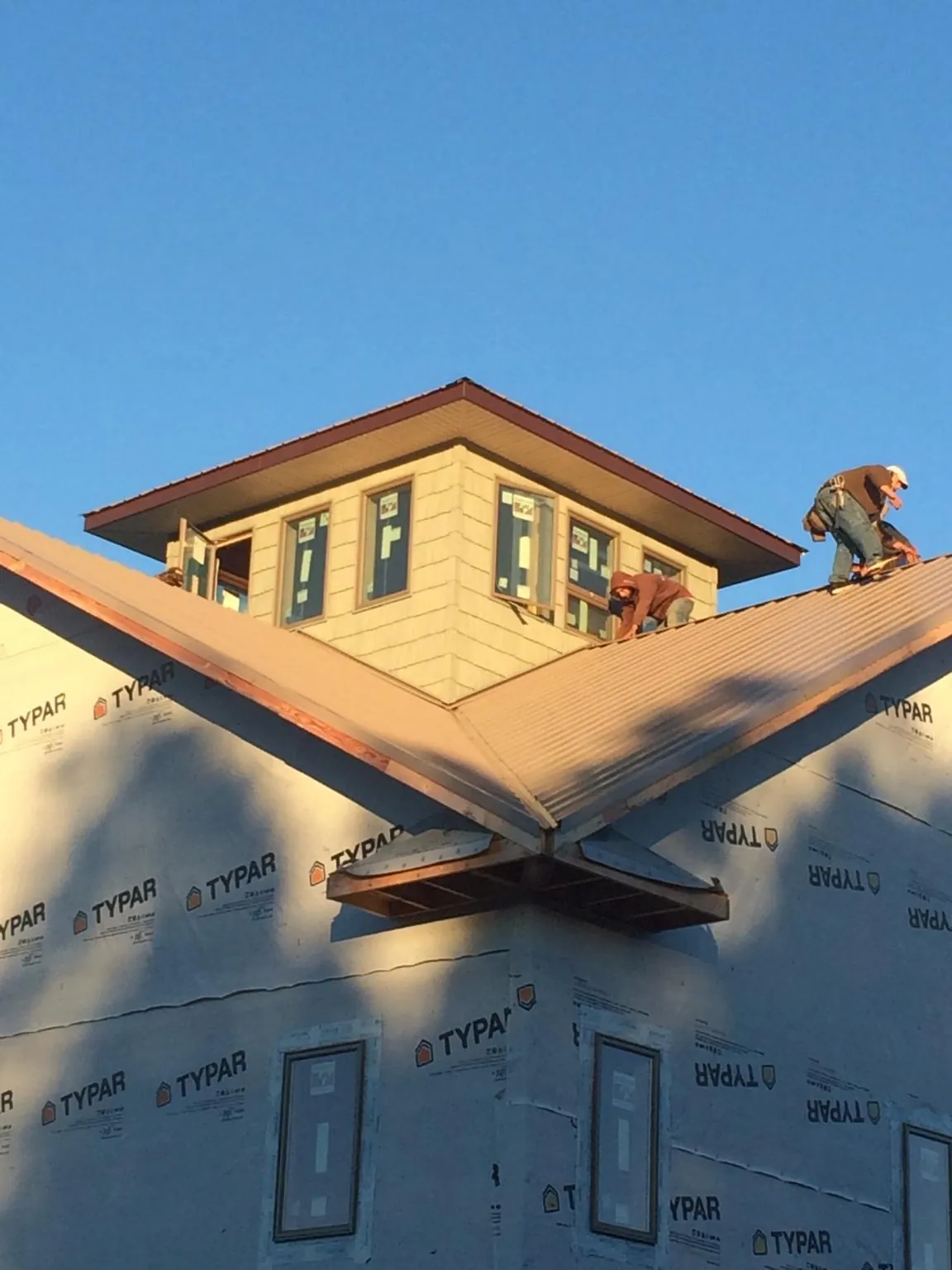 Roofers working around a rooftop cupola on a new metal roof at sunset — Roof Waterproofing in Rio Rancho by Roofing Brothers